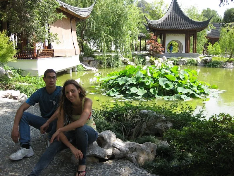 A girl and a boy sitting next to a pond in Huntington Gardens 