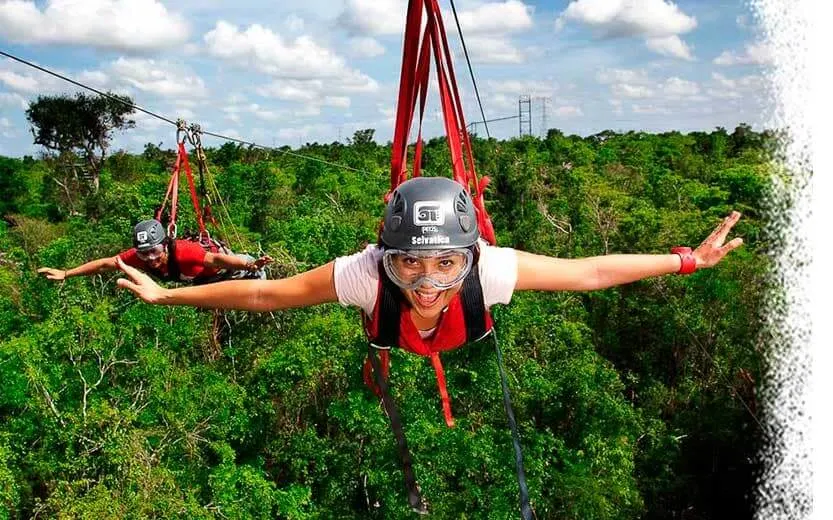 A woman ziplining above the trees in Selvatica Park