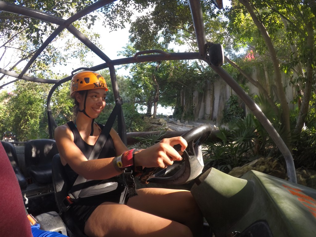 A woman smiling as she drives an ATV in Xplor Park, inserted in a post about the ideal Cancun itinerary