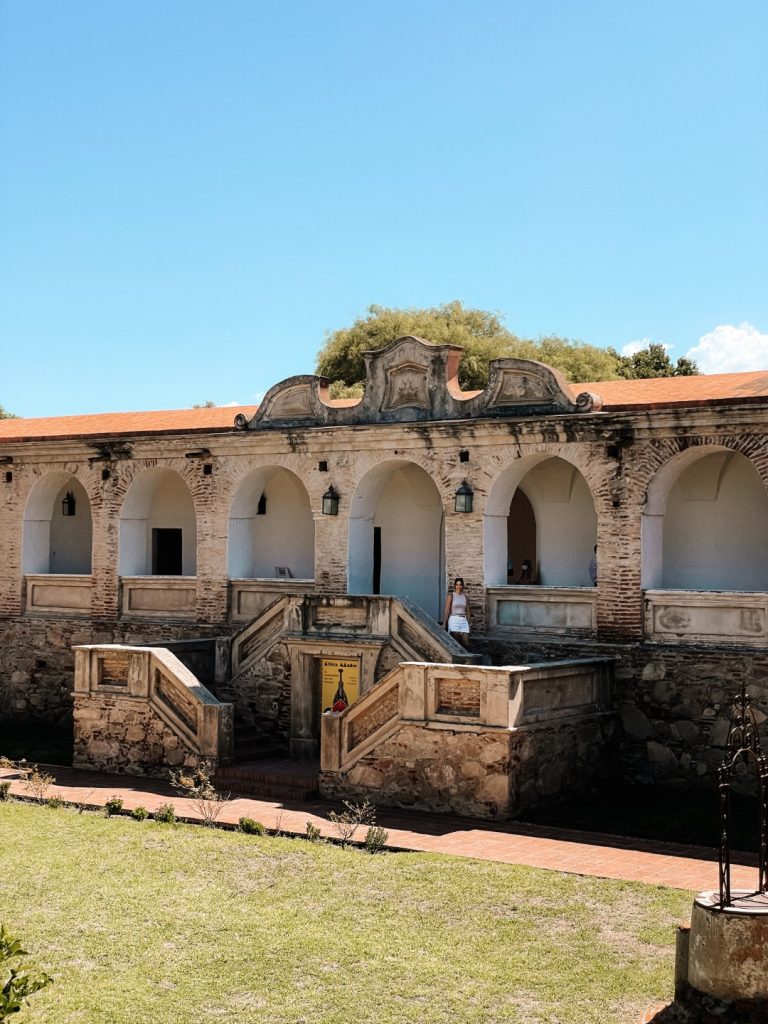 An old traditional building, and a woman standing on top of the stairs