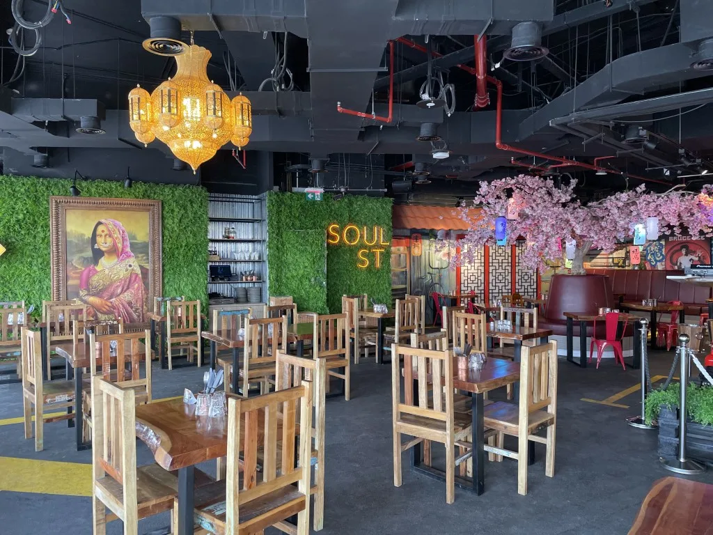 The interior of a restaurant with small square tables and chairs, and cherry blossom flowers