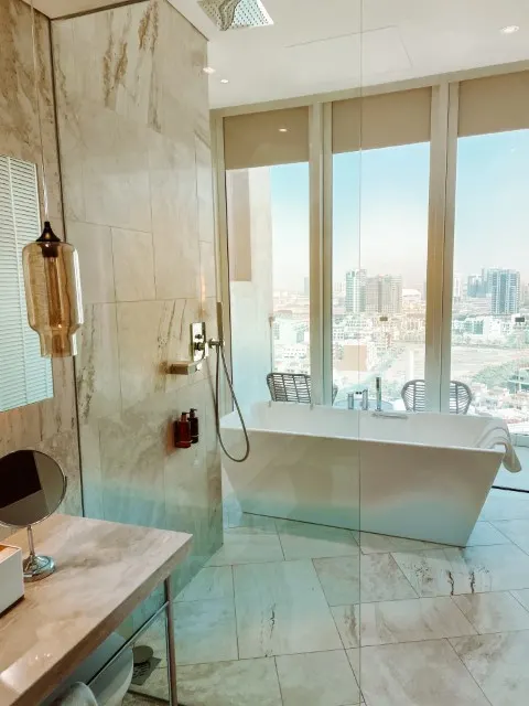 A hotel bathroom with a bathtub, and floor-to-ceiling windows