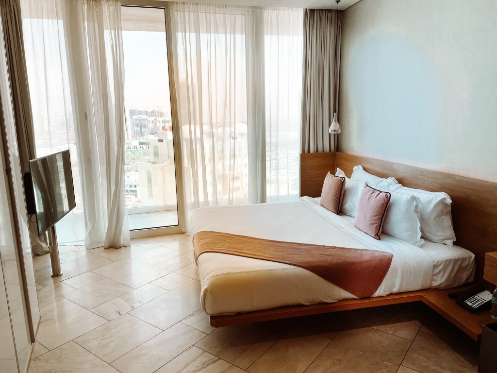 A spacious hotel room with a double bed, and floor-to-ceiling windows