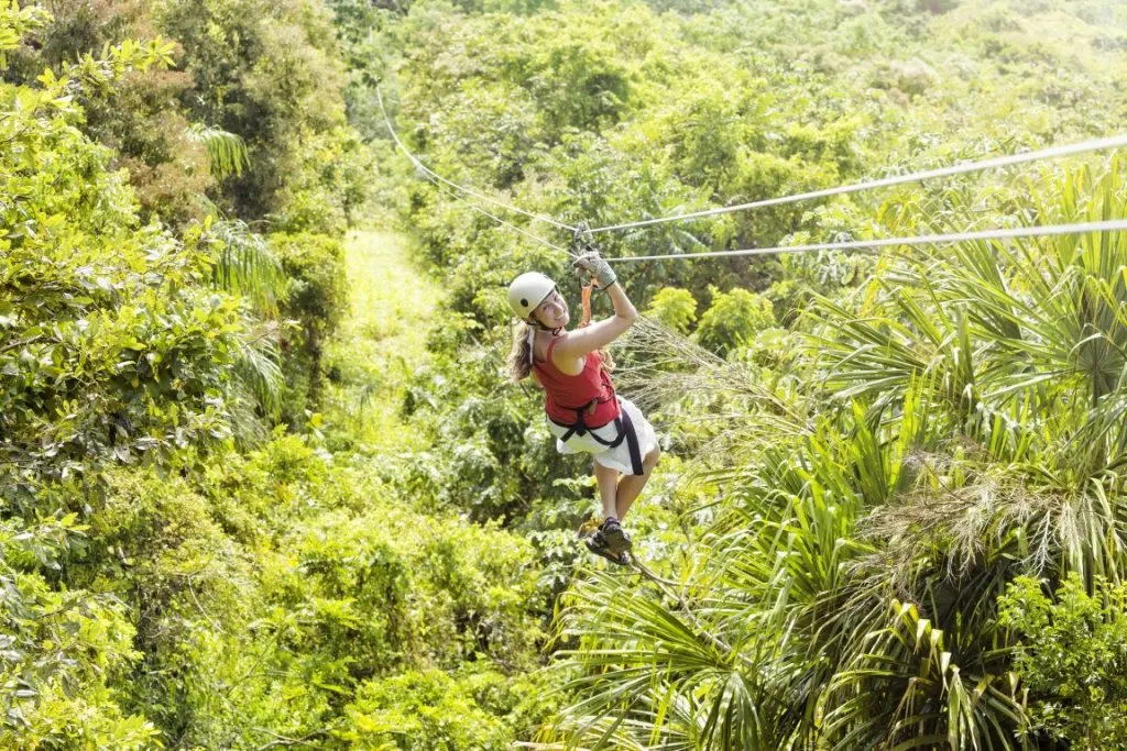 A woman ziplining over a lush jungle