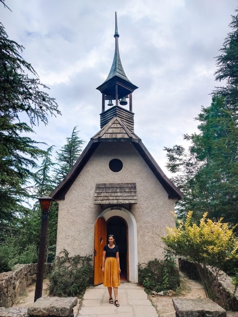 A woman standing outside a small church in the woods