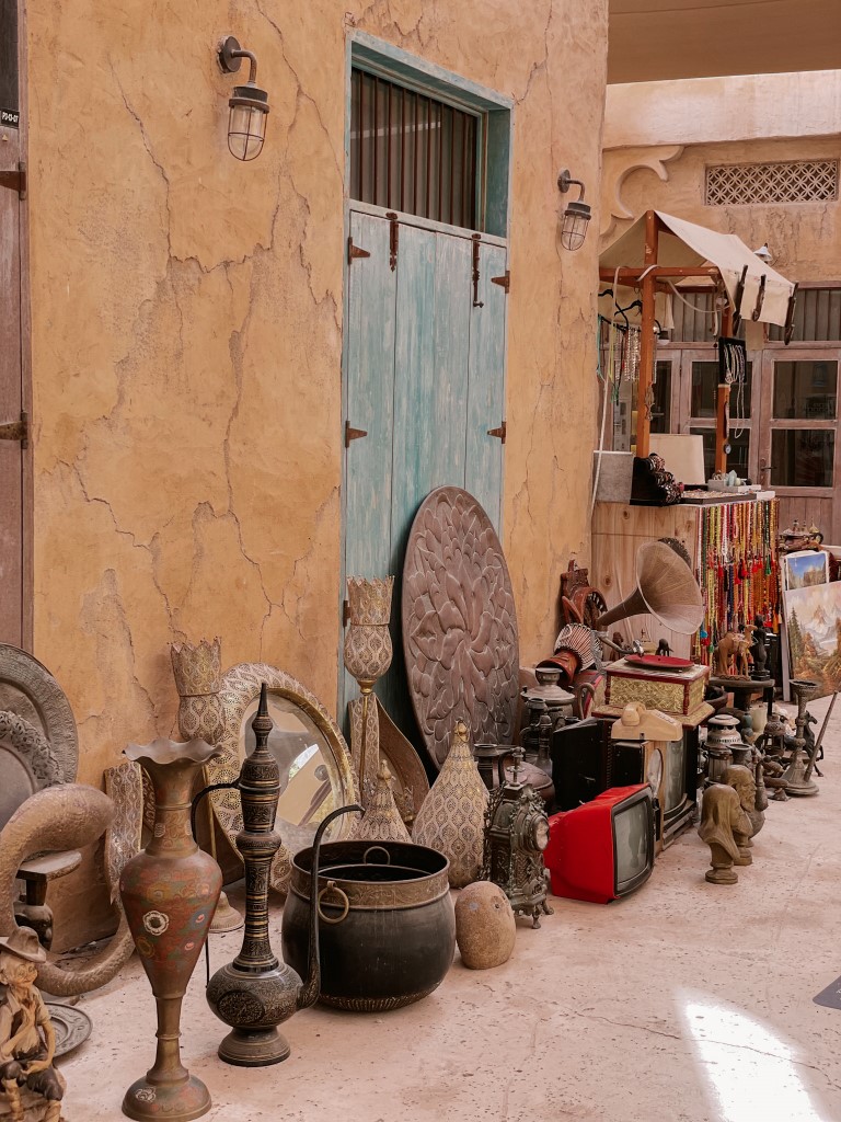 Antiques displayed on the floor, against an old-looking yellow wall 