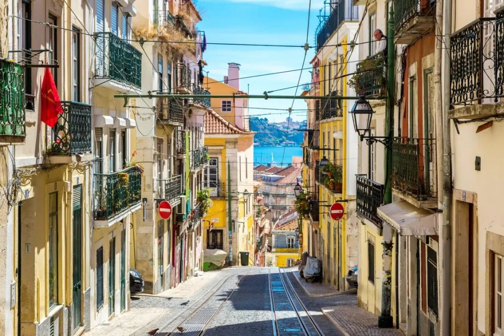 A hilly cobblestone street in Lisbon, lined by colorful buildings