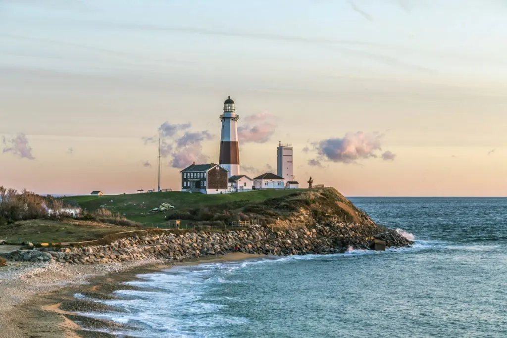 Image of a small cliff with a red and white lighthouse and small buildings on top, overlooking the sea, inserted on a post about taking a day trip to Montauk