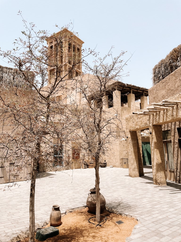 two trees in the middle of a square with traditional buildings around it