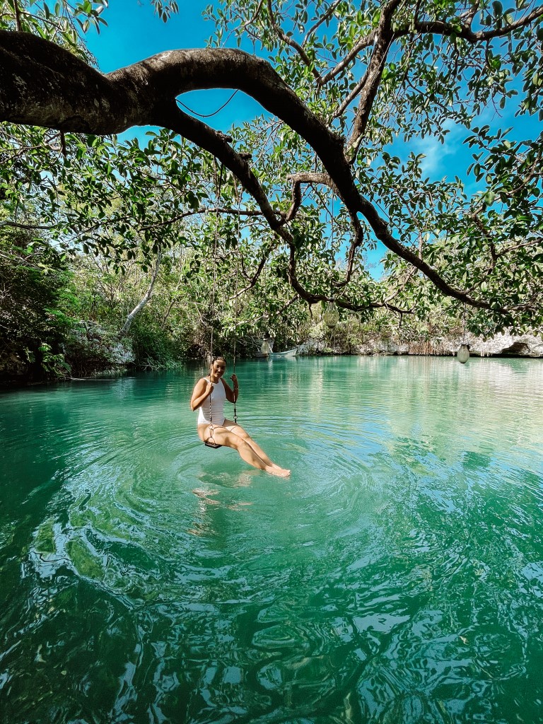Woman sitting on a swing in the middle of an open cenote.