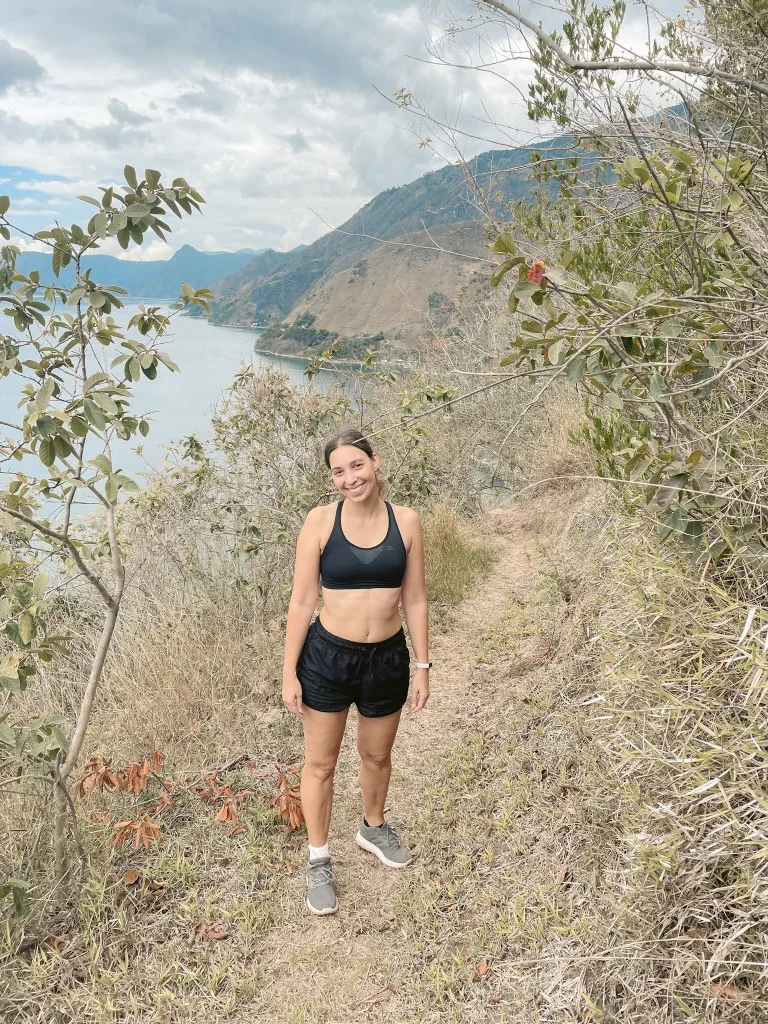 A woman wearing black shorts and a sports bra, hiking in Lake Atitlan 