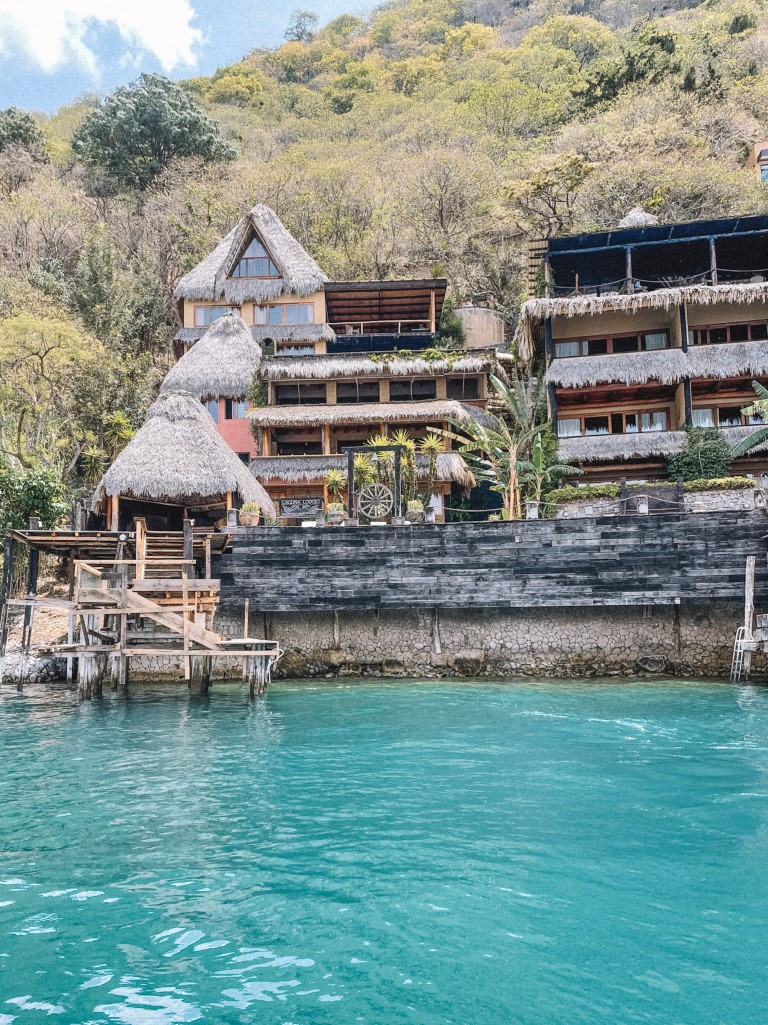 A thatched-roof hotel on the shores of a blue lake