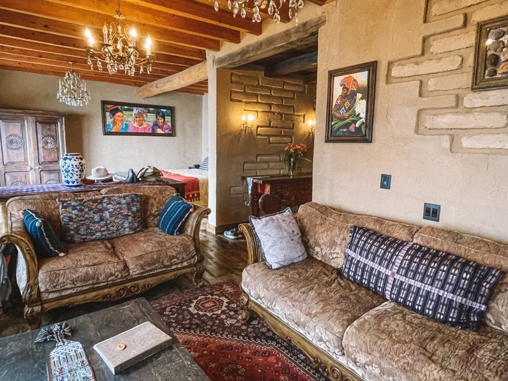 The cozy lounge area of an eco resort in Lake Atitlan, with two couches, a rug, and colorful portraits