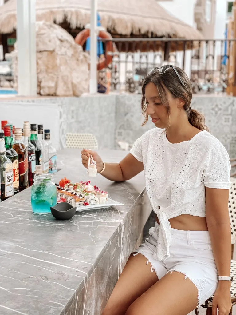 Image of a woman sitting at a sushi bar, eating 