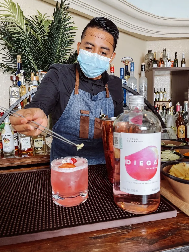 A barman decorating a drink at the bar at Wyndham Alltra Cancun