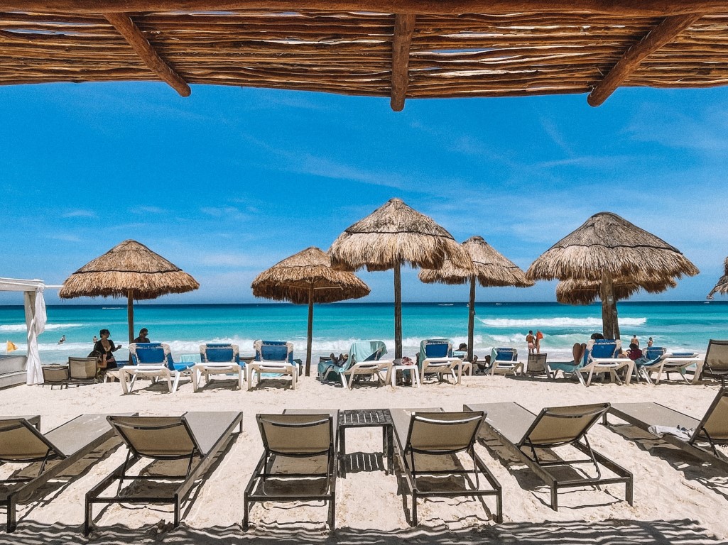 A beach club in Cancun, with sunloungers, palapas, and the blue sea in the distance