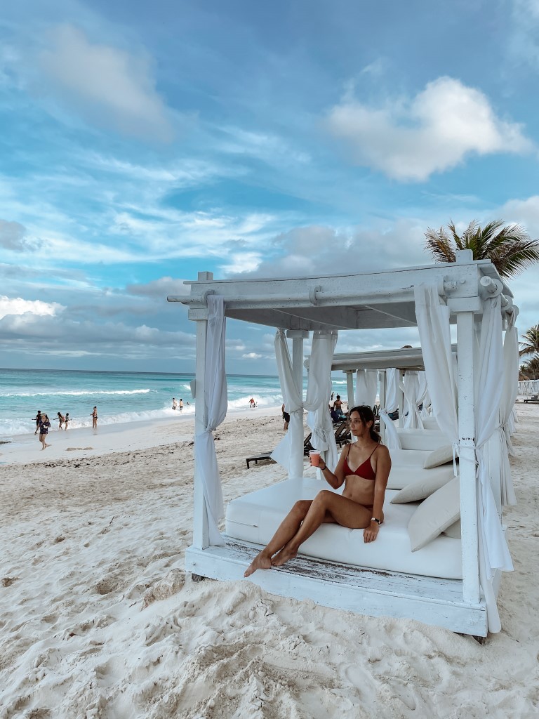 A woman in a beach cabana at Wyndham Alltra Cancun, holding a drink