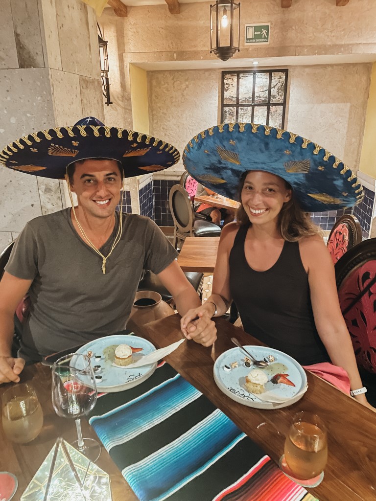 A couple wearing Mexican hats while having dinner at a restaurant