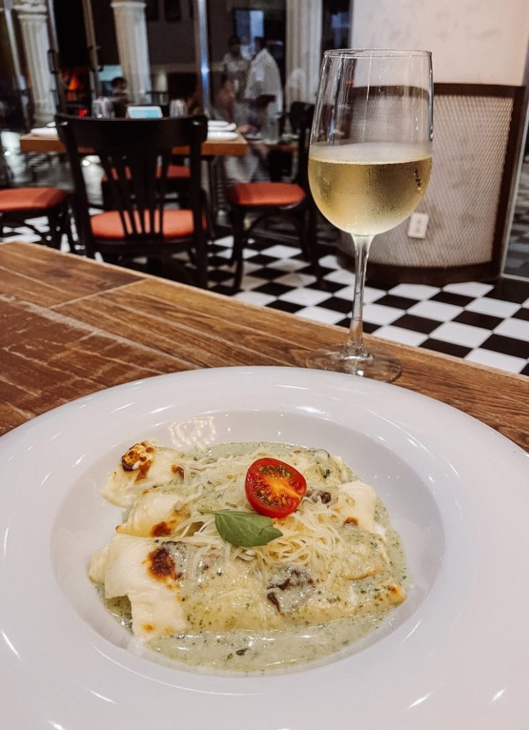 A dish of Italian cuisine placed next to a glass of white wine