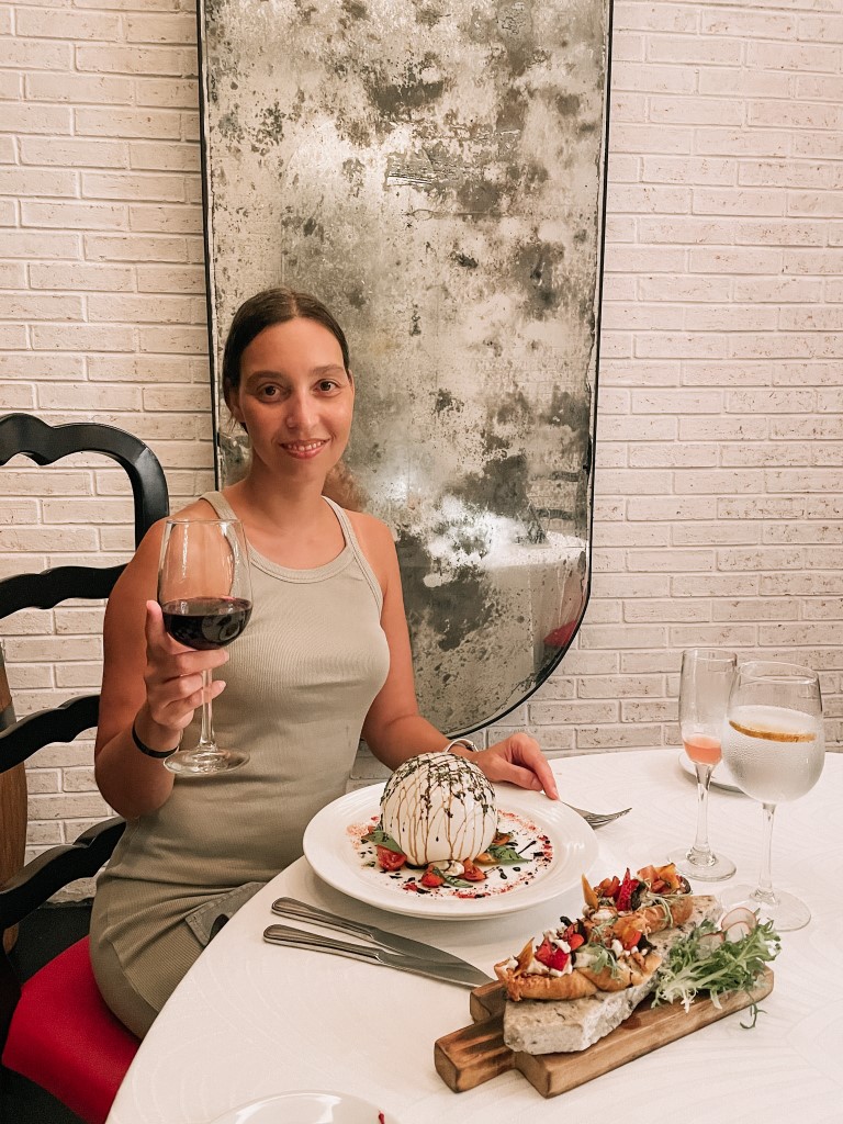 A woman at a restaurant, holding a glass of red wine