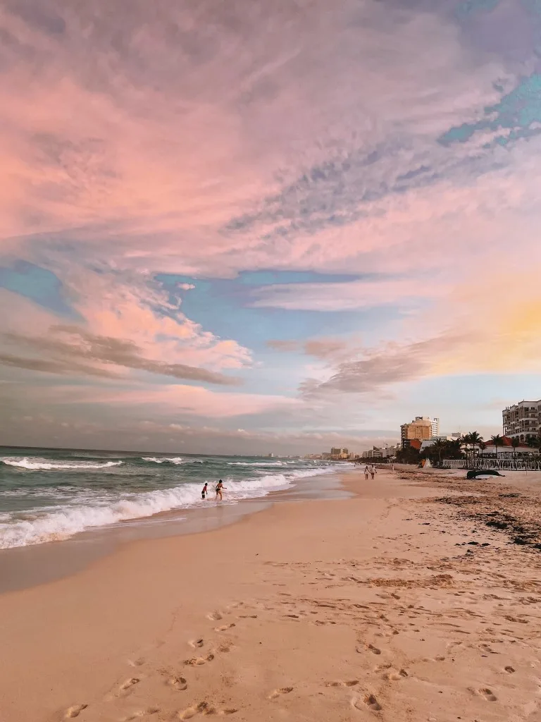 A sunset in Cancun, with pink clouds and an empty stretch of beach 