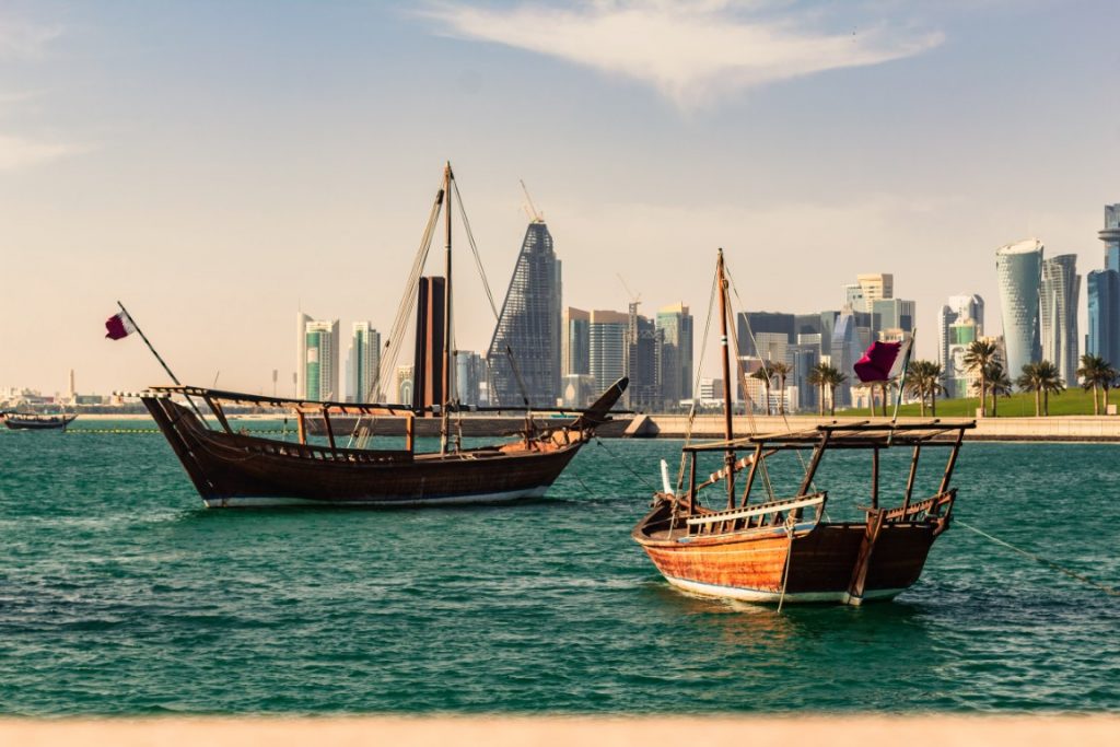 Image of traditional boats in Doha in front of skyscarpers, inserted in a post about the best places to visit in Qatar.