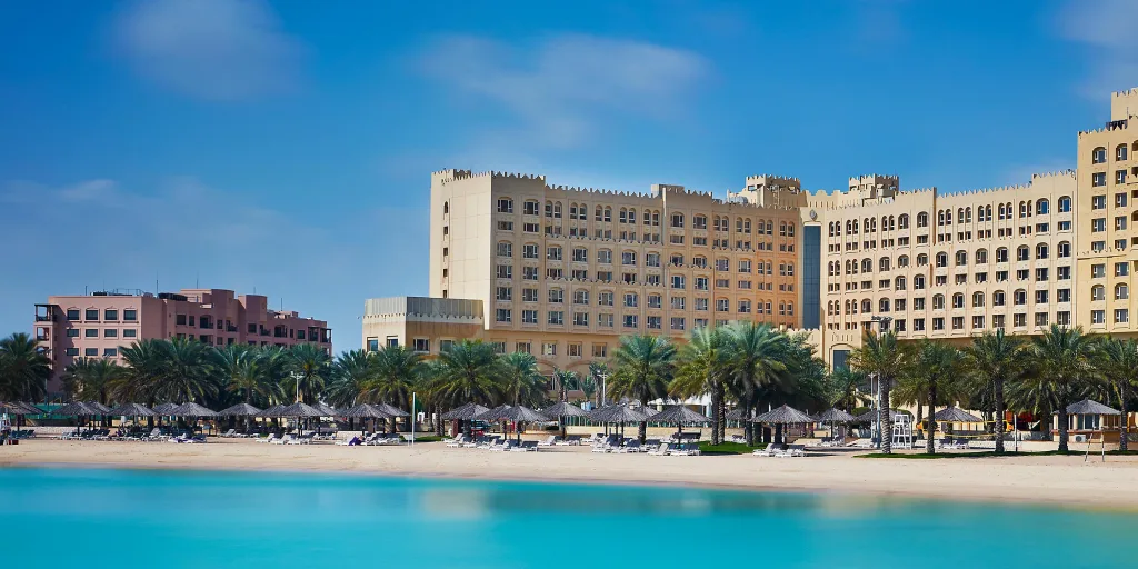 A great building with palm trees, a long stretch of white sand, and the sea in the forefront