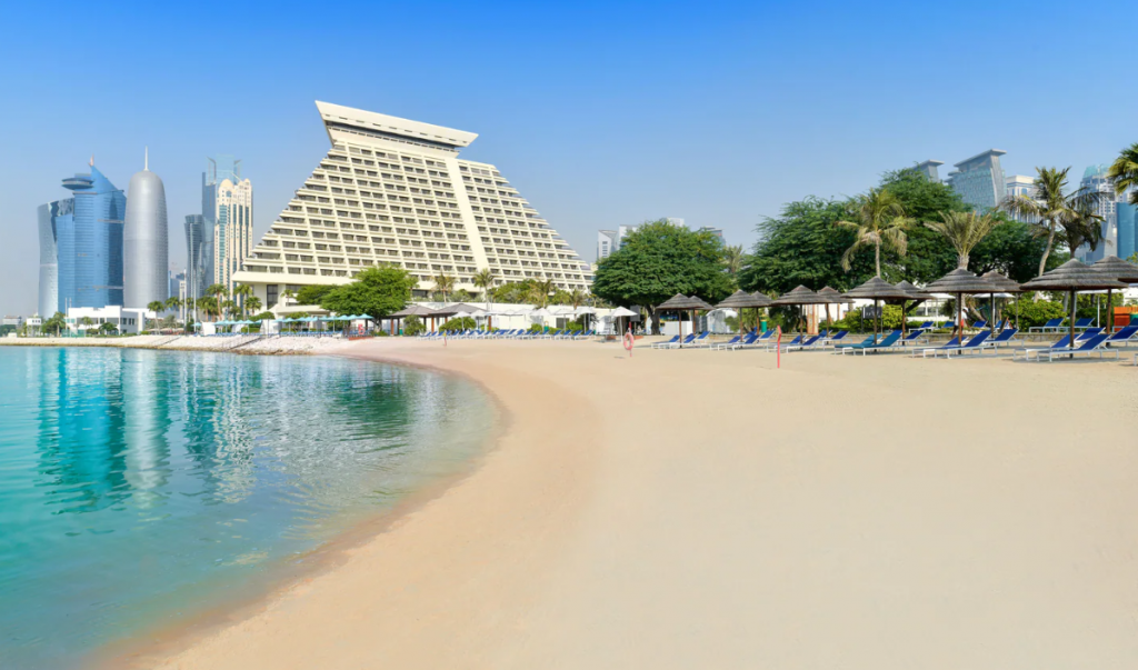 A wide beach area, and modern buildings in the background