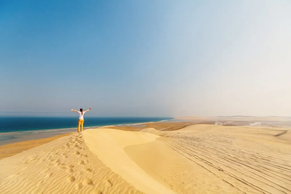 A woman standing on the ridge of a sand dune in the desert