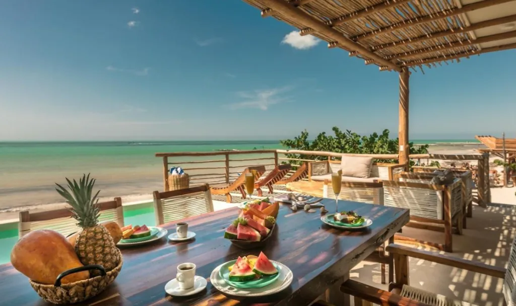 A table with plates of fruit, and the sea in the background