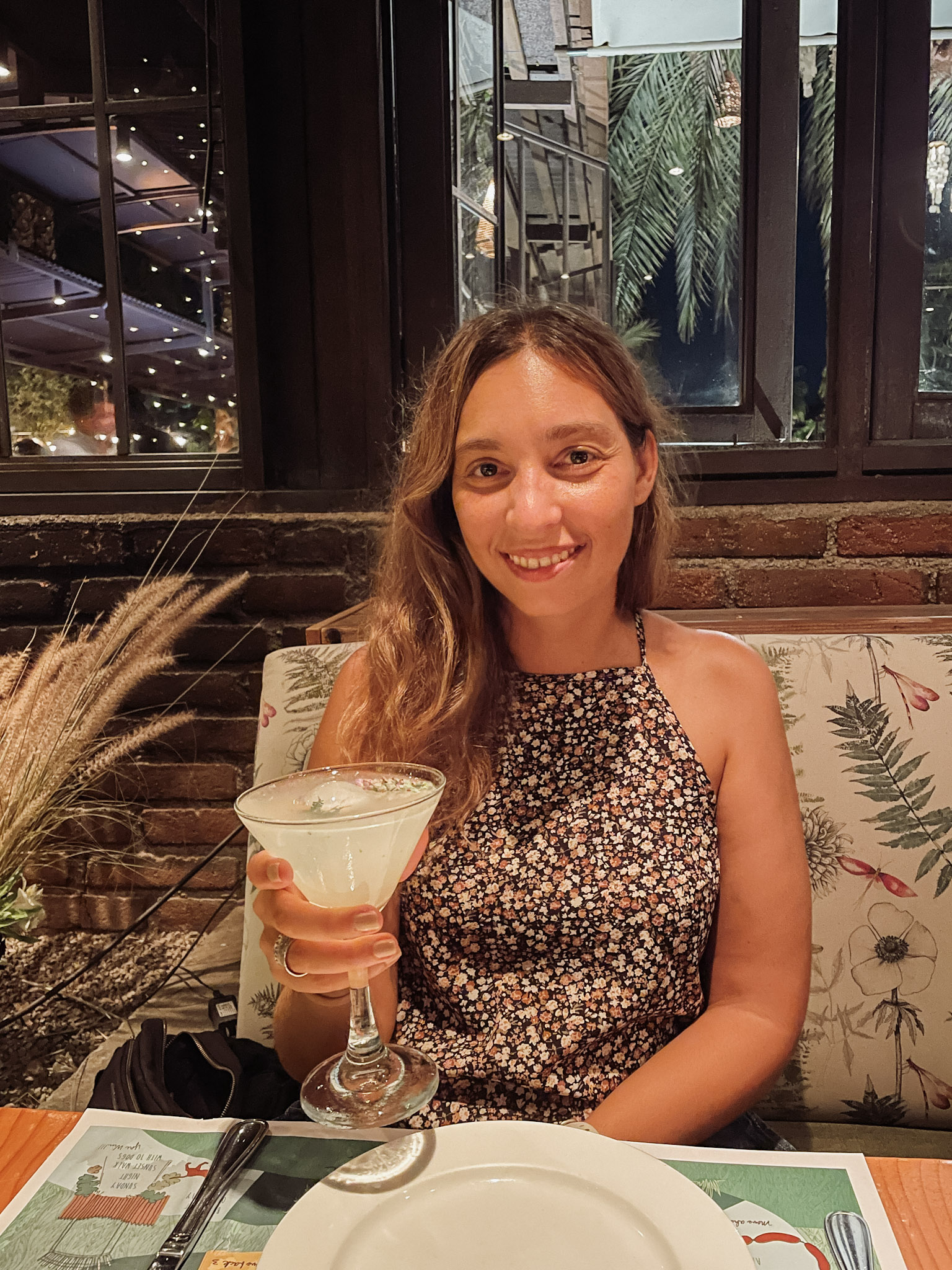 A woman dining a Flora Farms, holding a cocktail in her hand