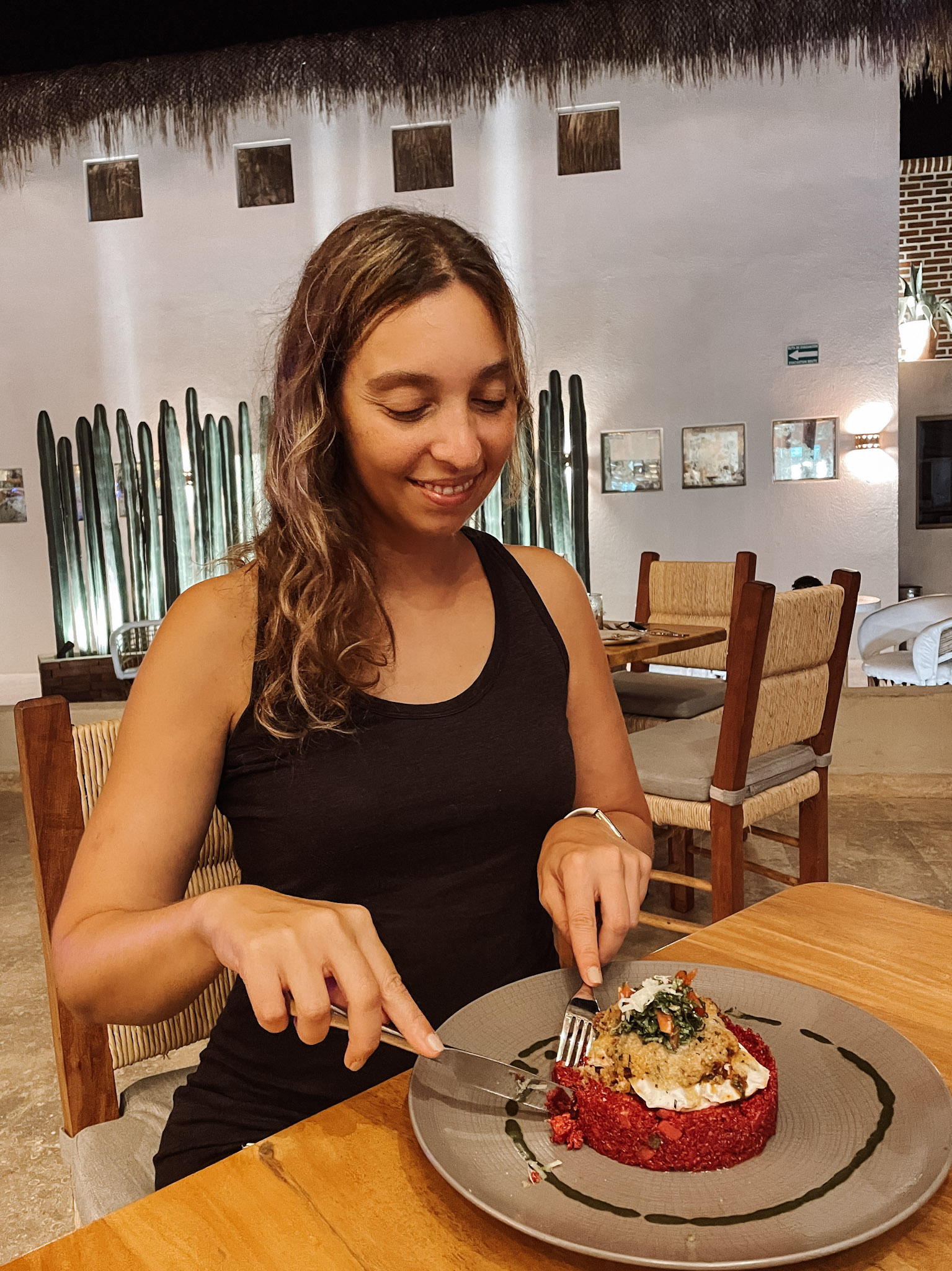 A woman smiling at her gourmet dish in Don Sanchez, a farm-to-table restaurant in Los Cabos 