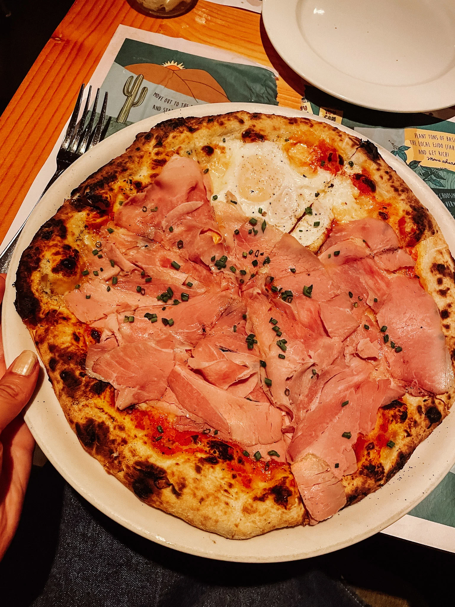 A round pizza in a white plate at Flora Farms in Los Cabos