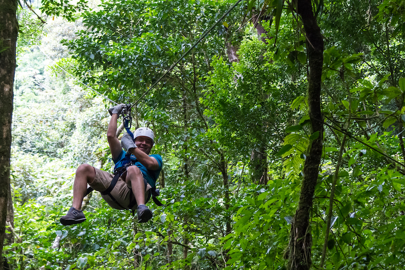 A man ziplining through the jungle vegetation