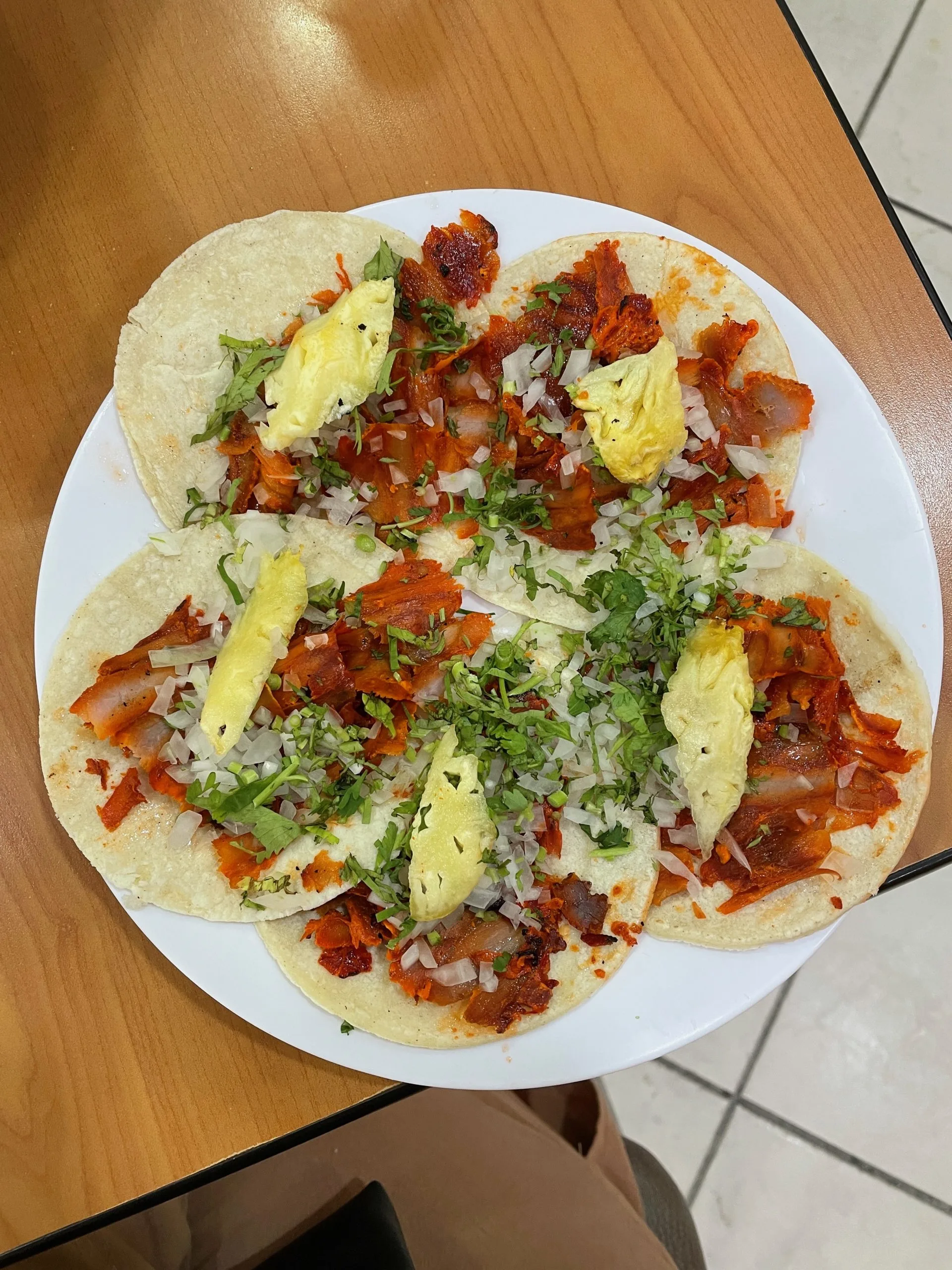 An overhead shot of a round white plate with five tacos in Cancun