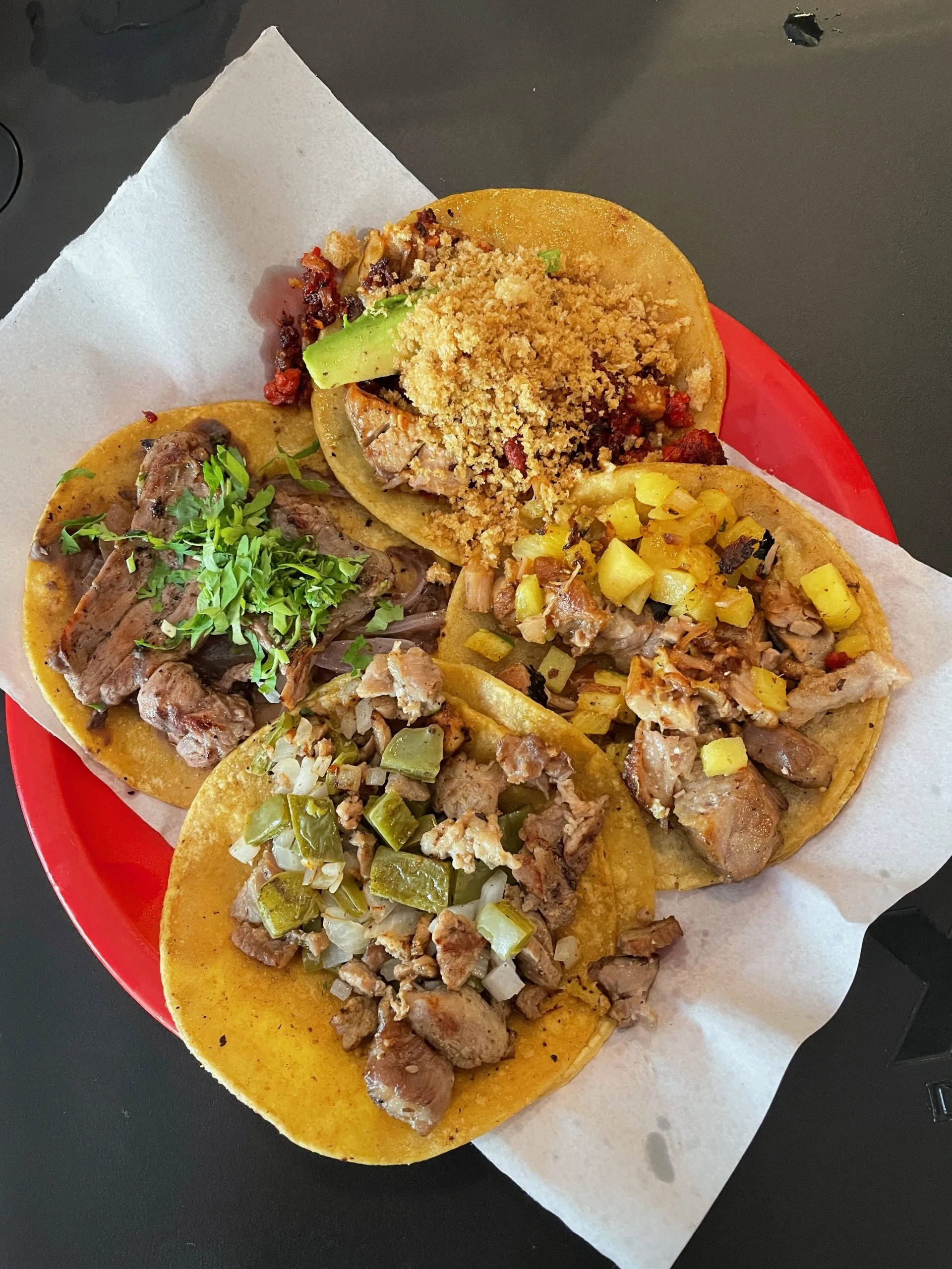 A red plastic plate with four tacos