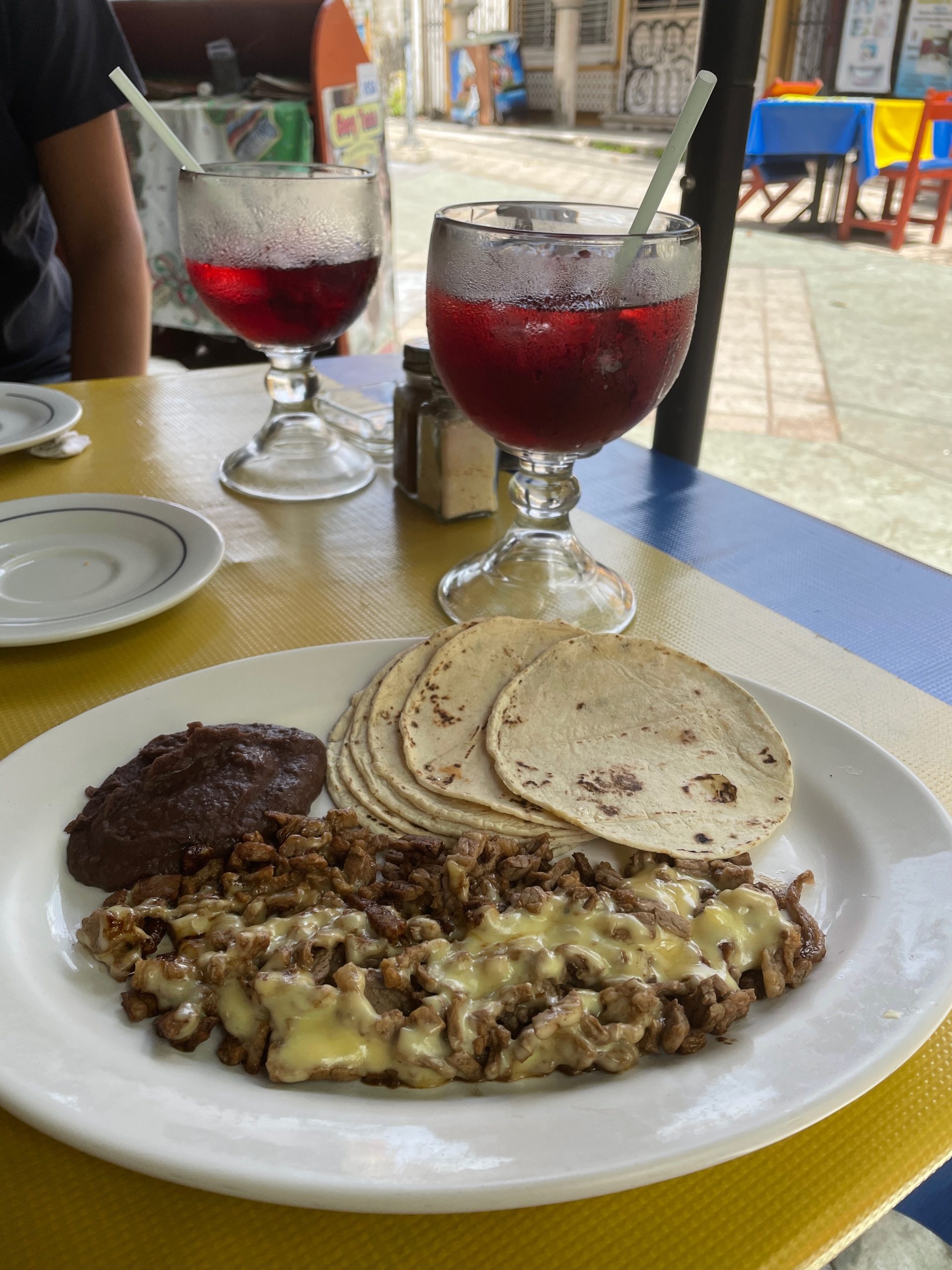 A plate with tortillas and taco fillings, and two glasses of red juice in the background