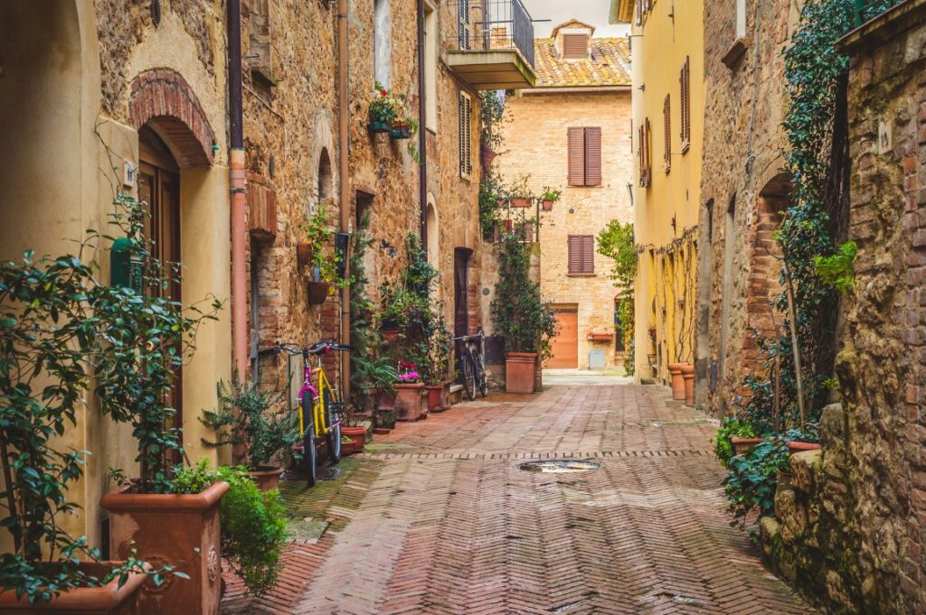 A picturesque street in Pienza, with old buildings and plant pots on both sides on a sunny day