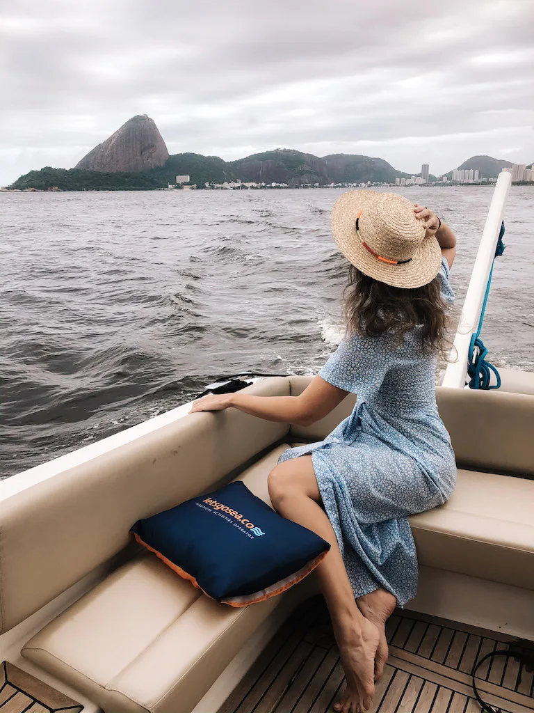 A woman wearing a blue dress and a hat, sailing in Rio de Janeiro