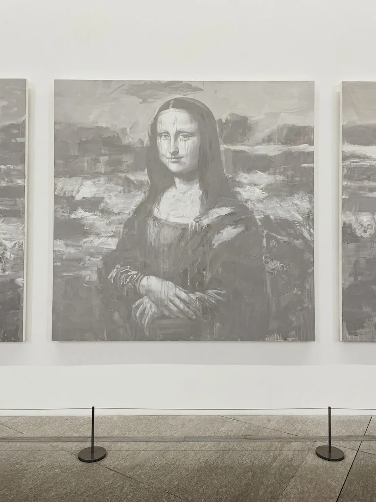 A painting of the Mona Lisa in black and white, against the white wall of a museum