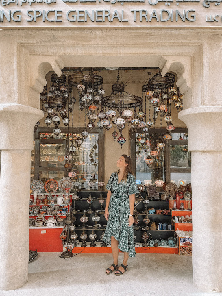 A woman in a green dress standing at the entrance of a lamp shop