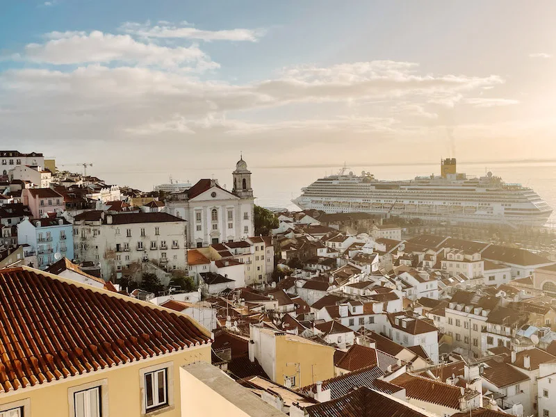 A sea of terracota rooftops in Lisbon, with a big cruise ship in the background