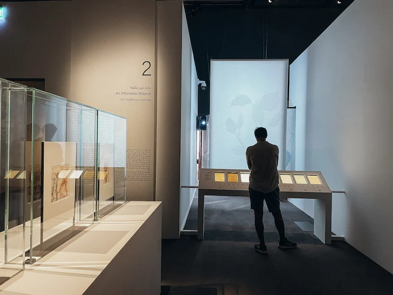 An exhibition room inside a museum, with a man reading the displays