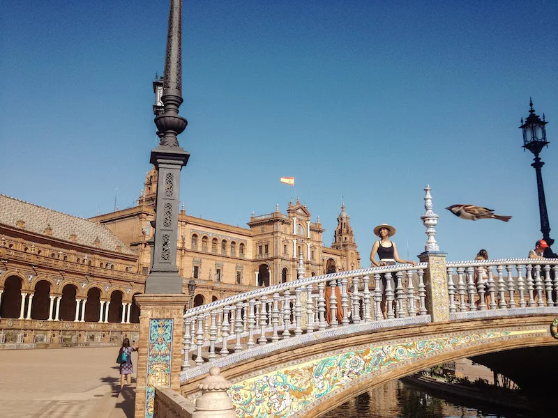 Image of a woman smiling on a beautiful bridge in Plaza de España, one of the most popular things to do in Seville 