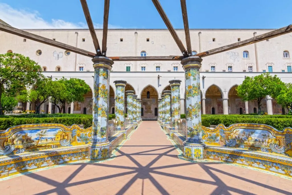 Image of Naples' Cloisters of Santa Chiara, with majolica tiles covering the columns and benches