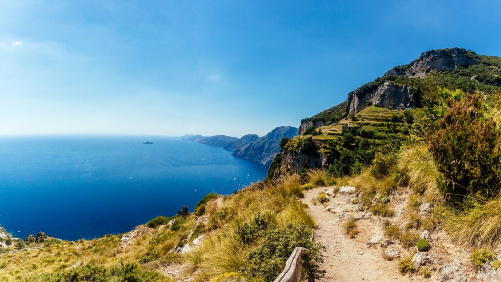 Image of a hiking trail on top of a cliff, with the blue sea on the left of the image, inserted in a post about the best things to do in Positano