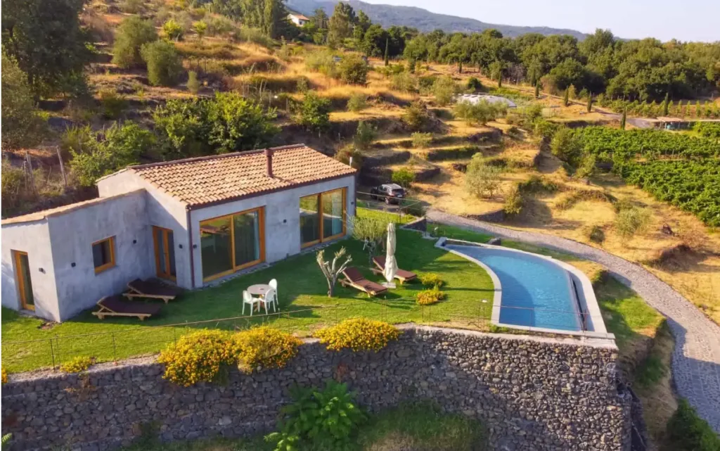 An eco-resort in Italy seen from above, surrounded by a garden with a swimming pool, and with vegetation in the background