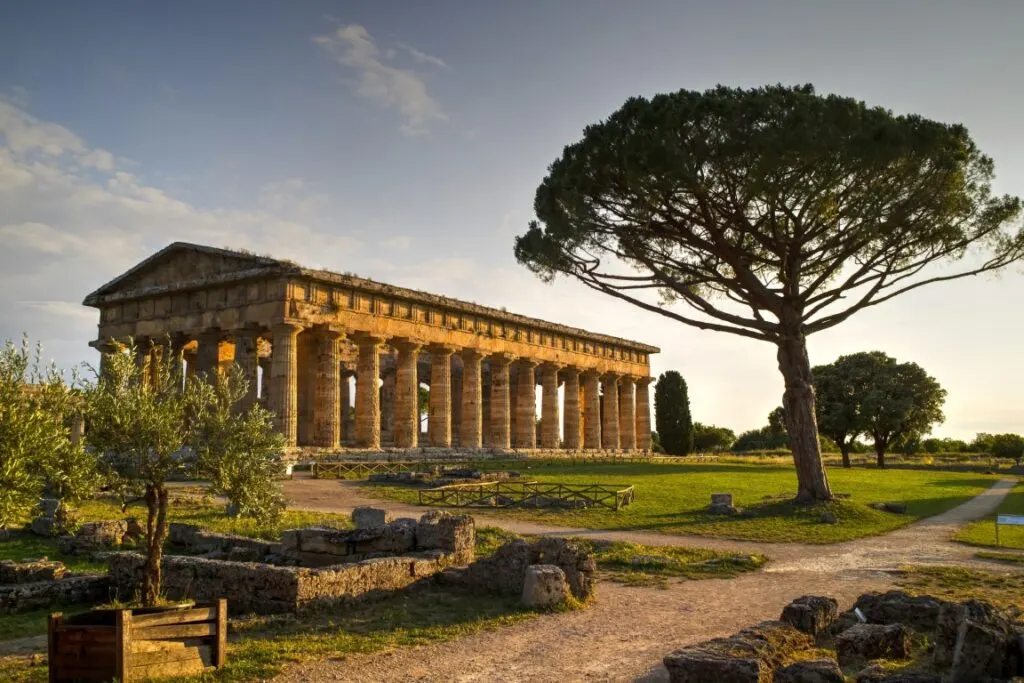 An ancient Greek structure in Paestum, surrounded by greenery 