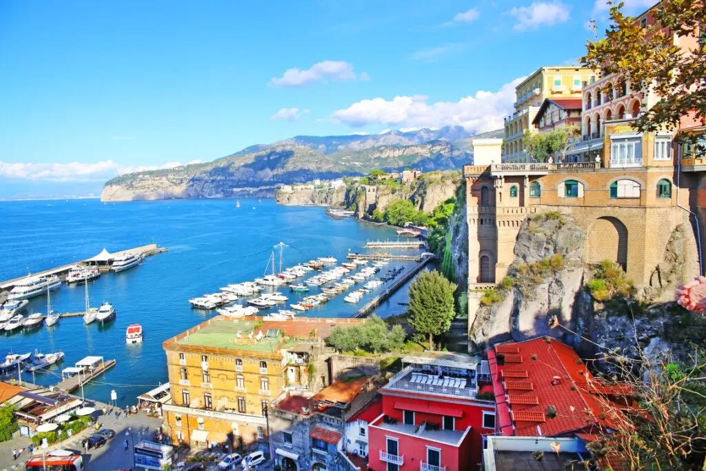 Image of Sorrento seen from a viewpoint, with the sea to the left and the rigged coastline and houses on the right. 