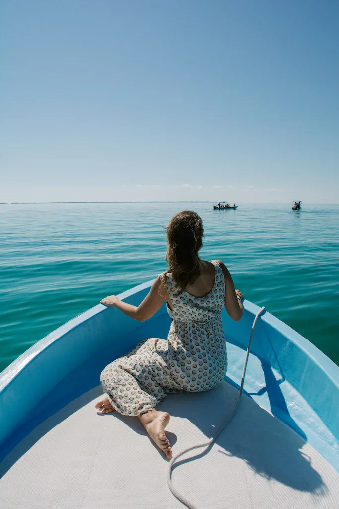 Woman from the back sitting on a blue boat.